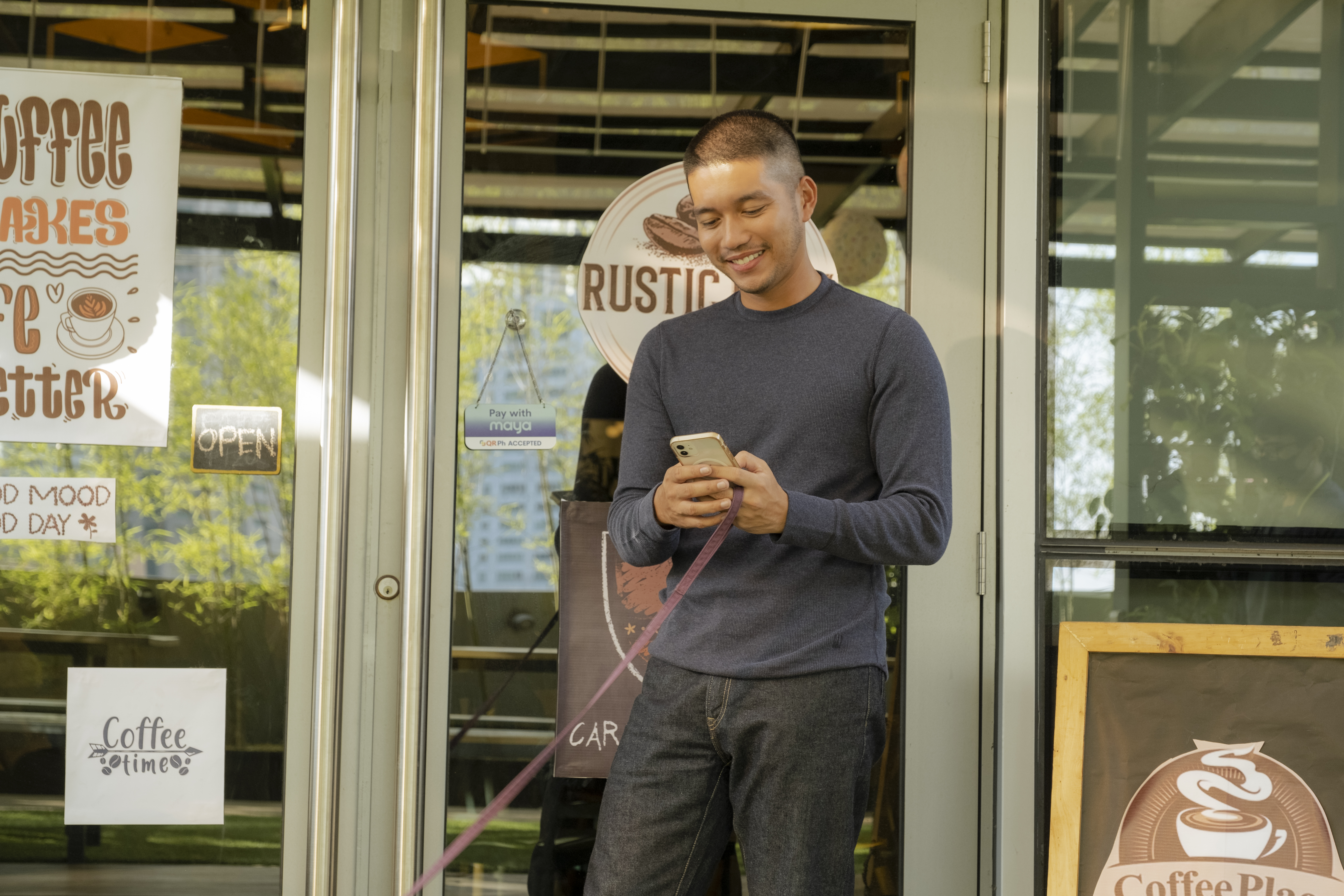 man using phone in front of rustic café