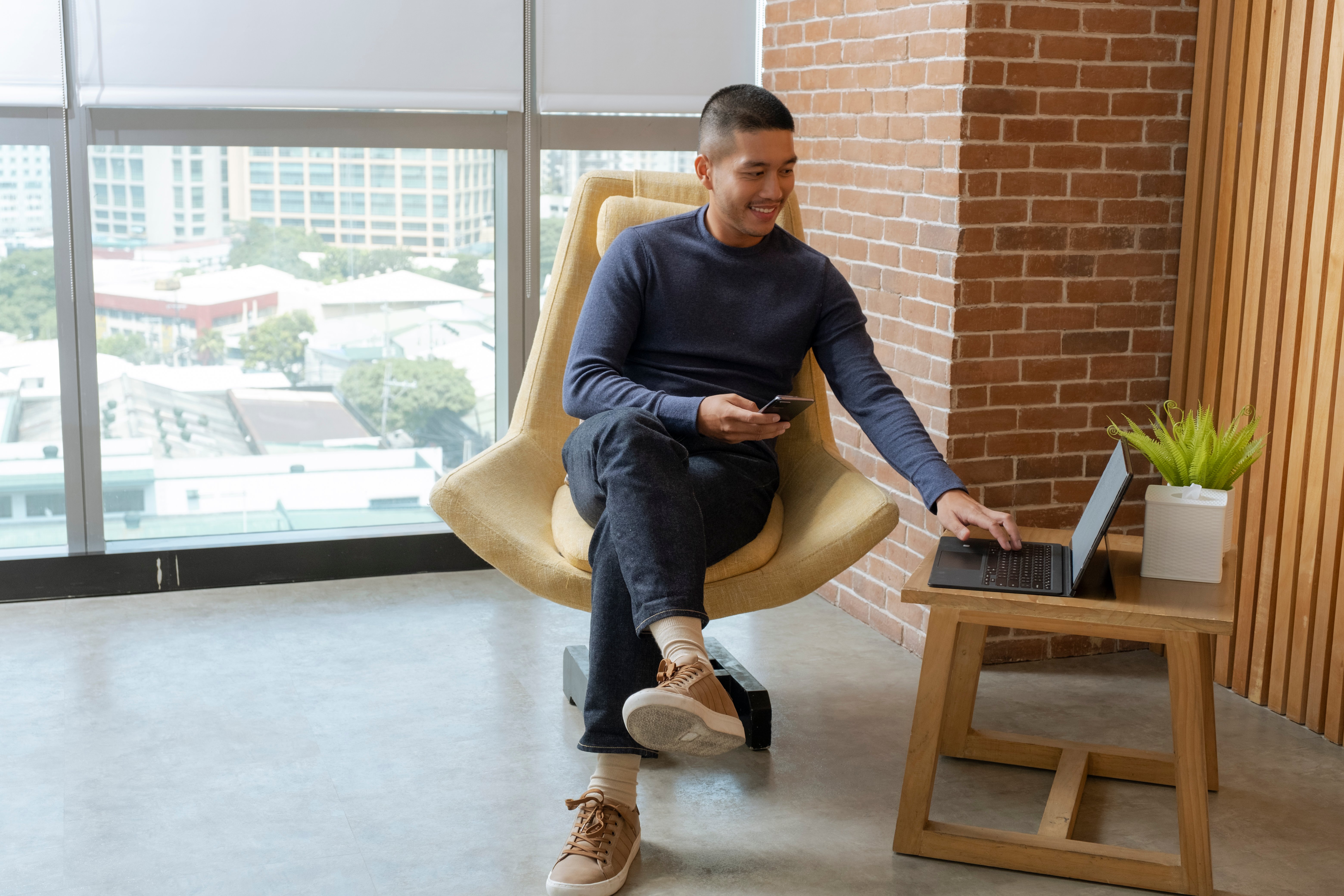 man checking phone and laptop